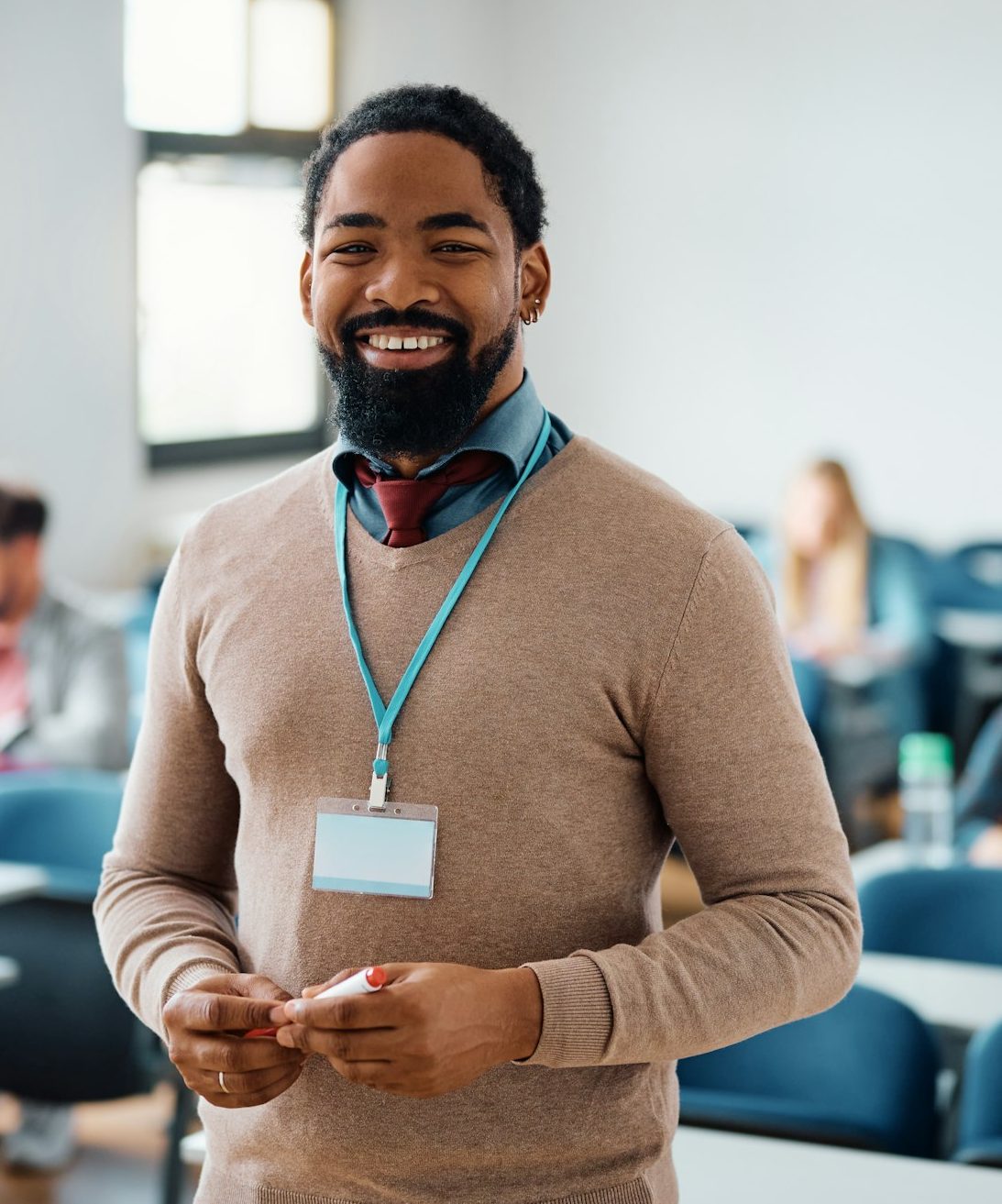 Happy black adult education teacher in lecture hall looking at camera.