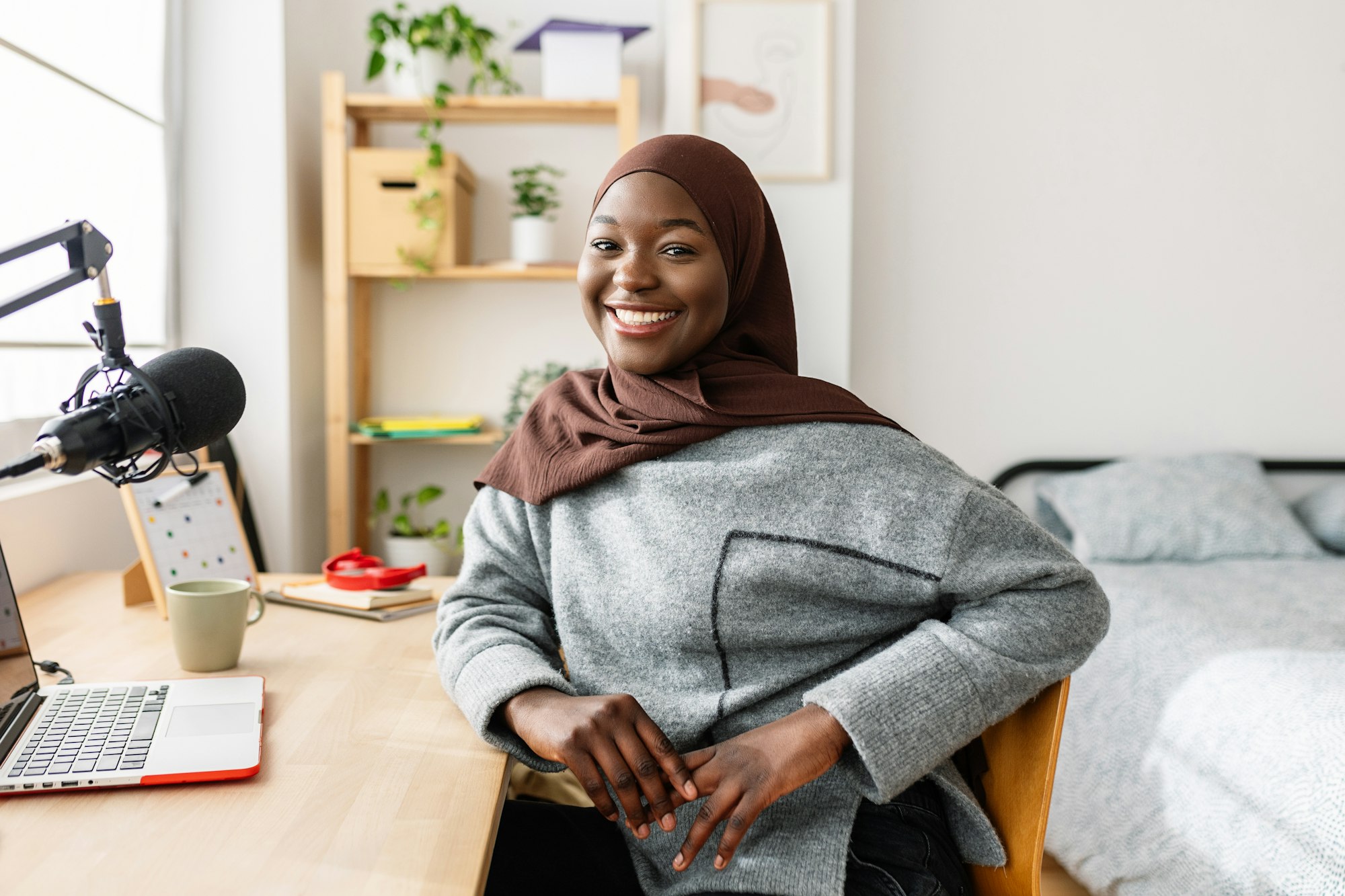 Portrait of young black woman smiling at camera sitting at desk